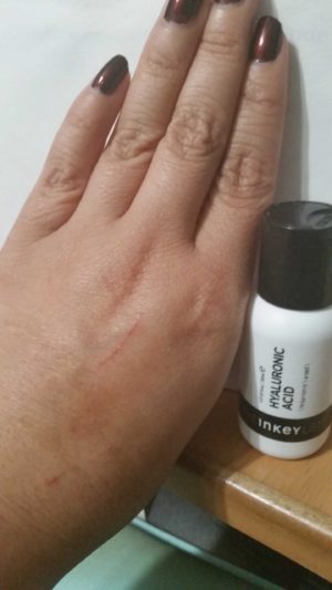 The INKEY List Hyaluronic Acid serum on the back of my hand with bottle next to my hand.