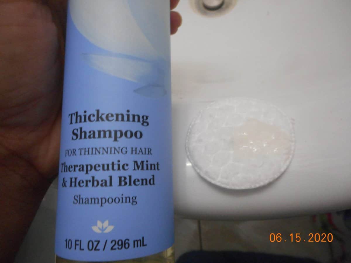 Derma-E Thickening shampoo bottle with shampoo on a cotton pad