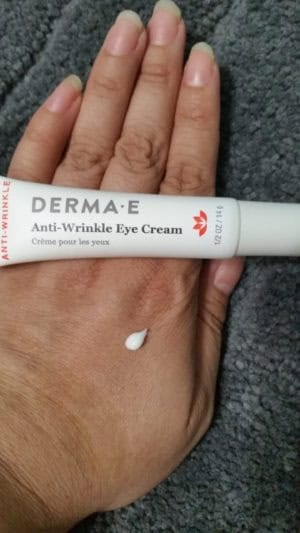 Derma-E anti-wrinkle eye cream tube on my fingers. A small amount of anti-wrinkle cream on my hand.