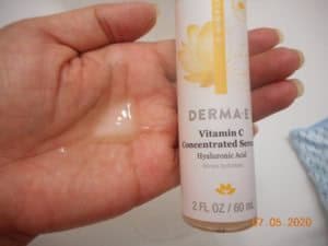 Derma-E Vitamin C Concentrated Serum in my hand next to container.
