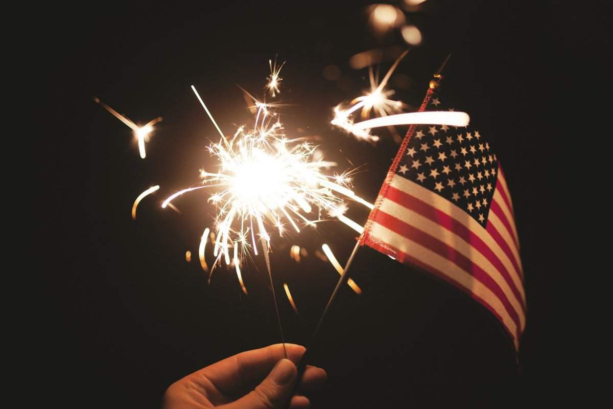 lit sparkier with an american flag in a person hand.