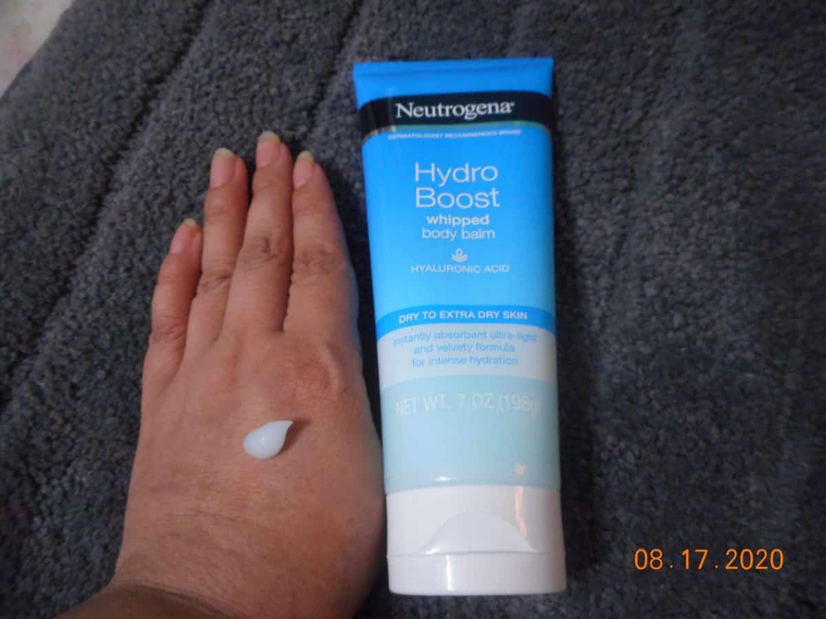 Neutrogena® Hydro Boost Whipped Body Balm tube next to my hand. Body Balm on my hand.