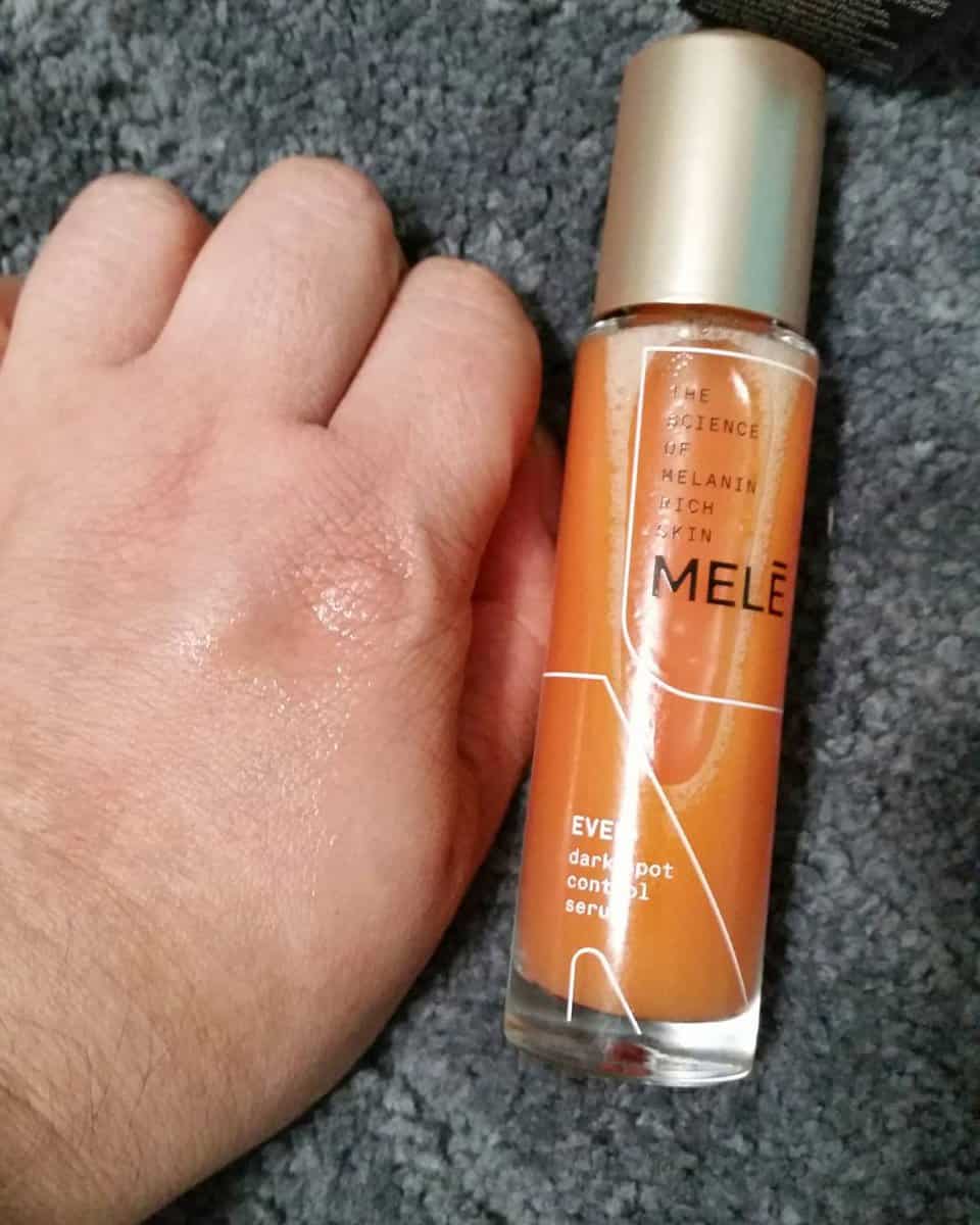 Mele Even Dark Spot Control Facial Serum bottle next to my hand. Serum on my hand.