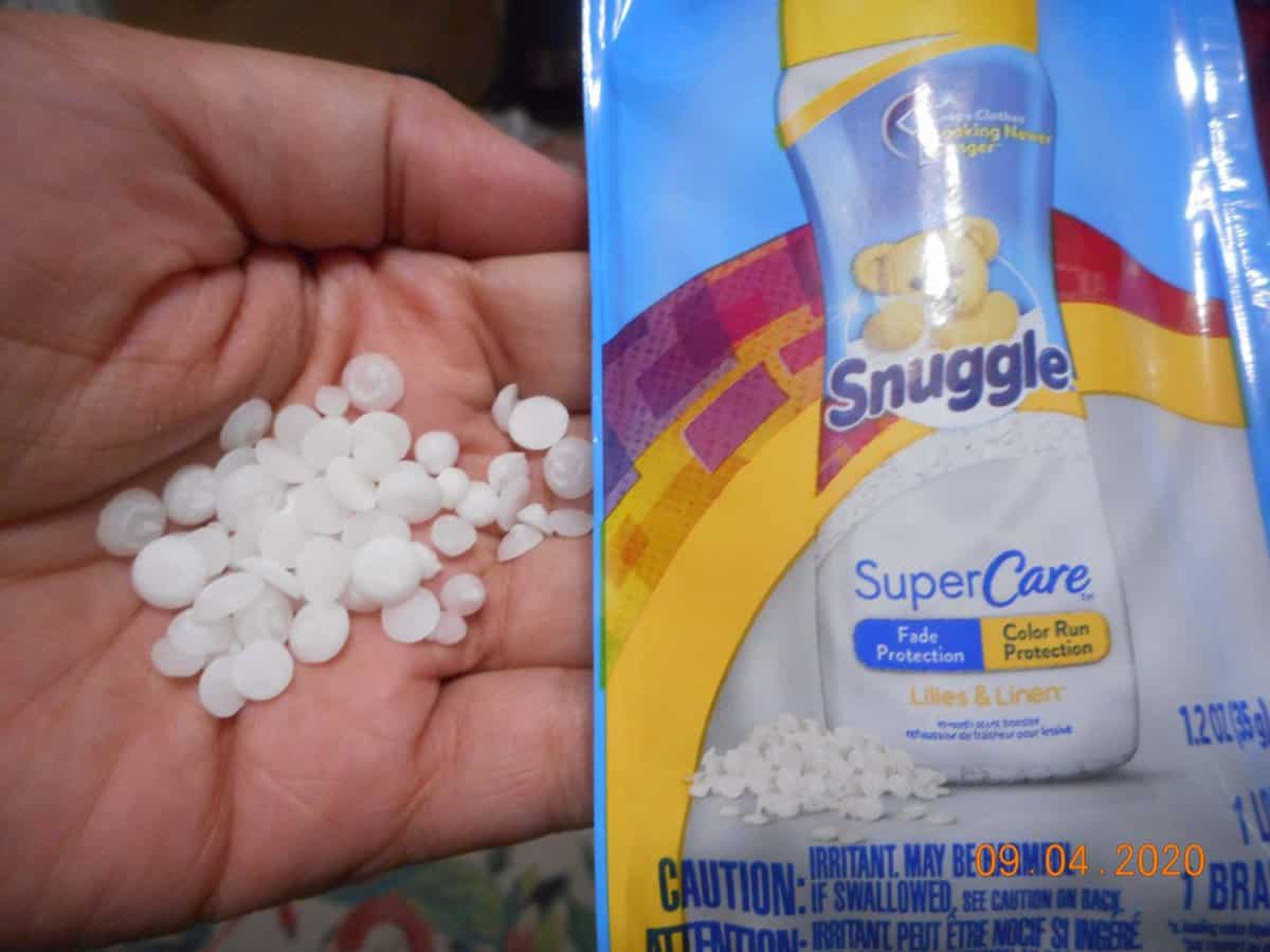 Snuggle® SuperCare™ Lilies and Linen scent boost packet. with scent boost beads in my hand.