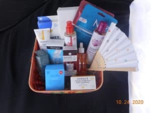 a basket filled with skincare products. Pimple treament products, face oils, serums, eye gels, cleansers, toner, sheet masks, moisturizer, and a fan.