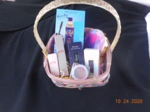 a smaller basket filled with beauty products. A gift set mascara and primer, lipsticks, blush, nail polishes, and an eye shadow palette.