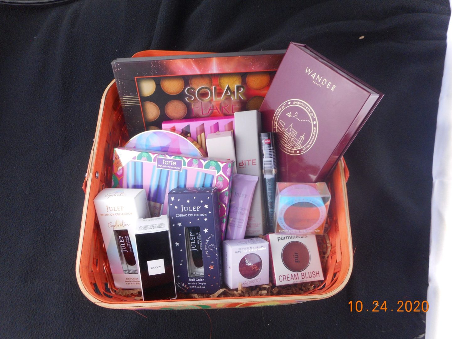 a basket filled with beauty products. Makeup, nail polish and eye shadows. Along with lip products.