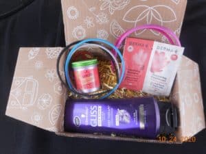 a box filled with crinkle paper. Also filled with colorful head bands, hair shaping putty, a sample of shampoo and conditioner and a large bottle of conditioner.