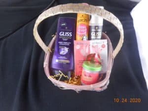 a smaller basket filled with hair care products. hair putty, sample shampooo and conditioner, shine spray, bottle of dry shampoo, and a large bottle of conditioner.