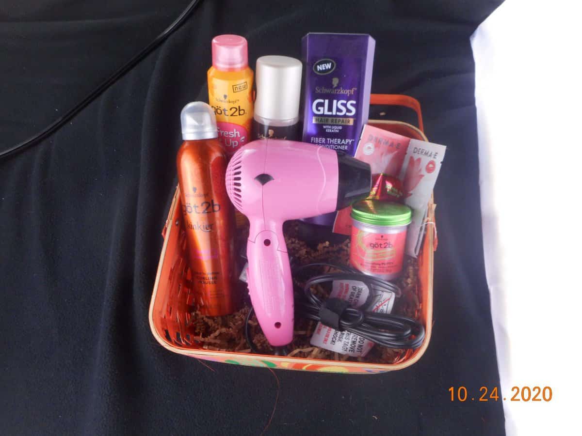 2nd image of basket filled with hair care products. dry shampoo bottles, conditioner, small hair dryer.