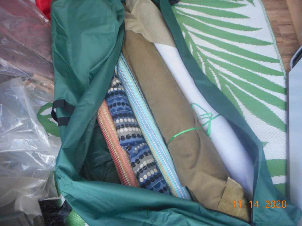 Christmas tree storage bag filled with rolls of fabric. open The Christmas tree storage bag is green with black accent.