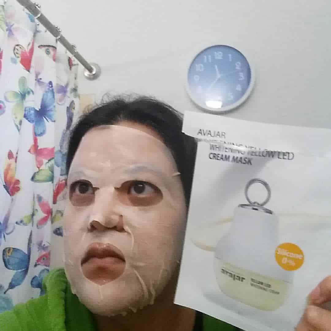 AvaJar whitening Yellow LED cream mask. Sheet mask applied to my face with packet in my hand.