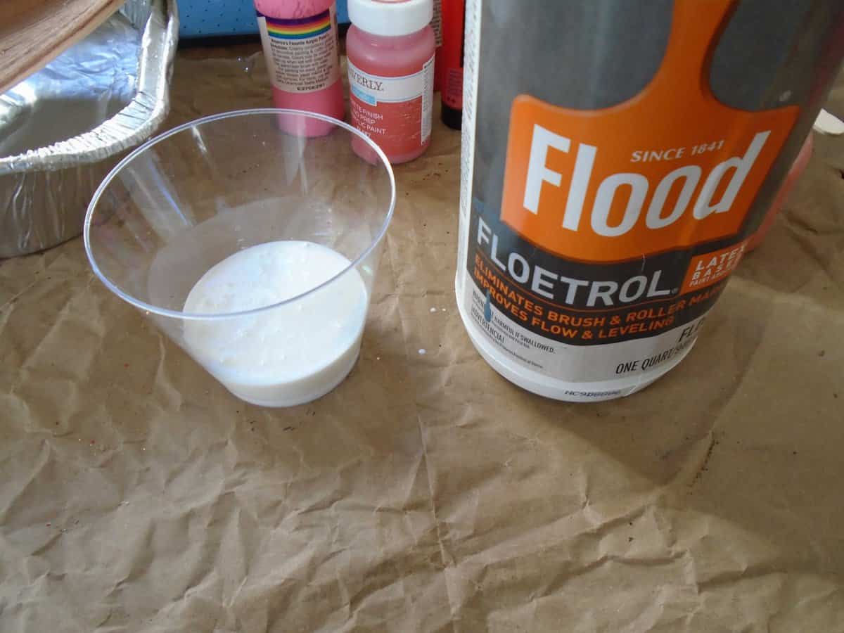 flood floetrol in a plastic cup. white liquid in plastic cup.