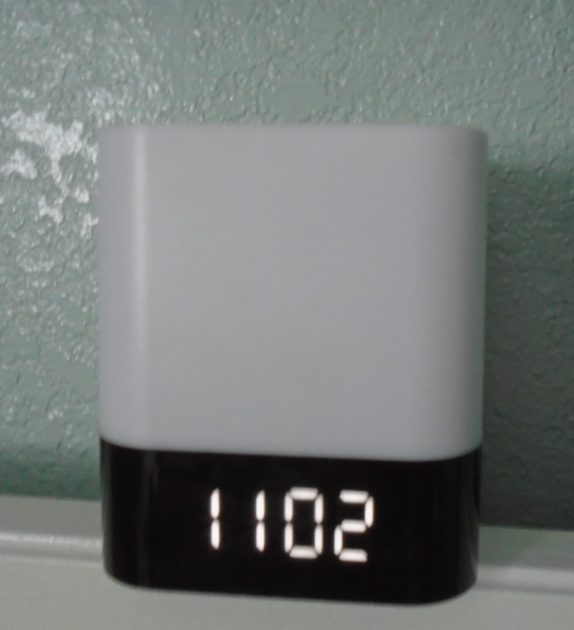 square Bluetooth speaker displaying time.