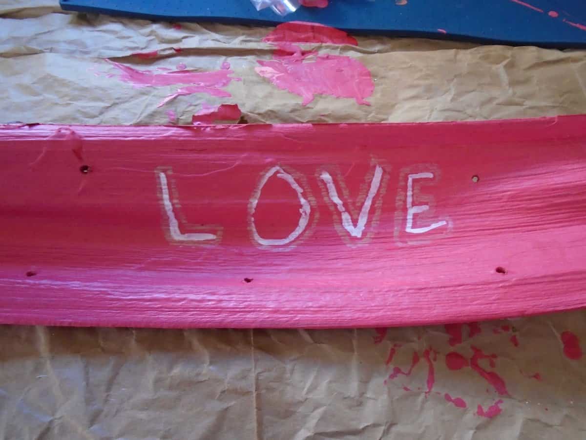 Love in white on pink background outlined with gold paint marker.