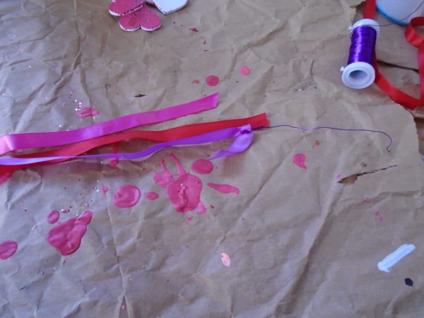 purple craft wire attached to purple ribbon. red and pink ribbon and purple spool of craft wire also in photo.