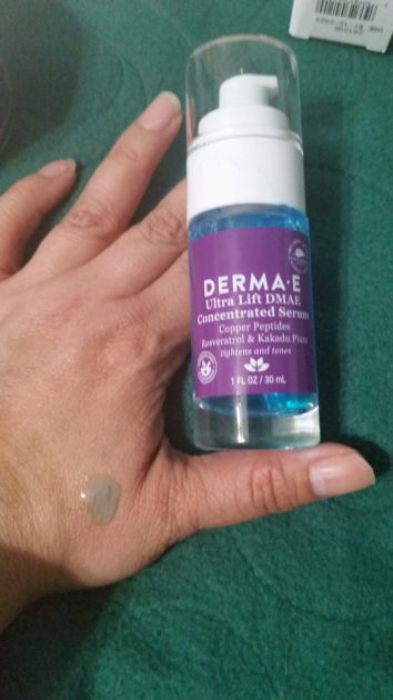 Ultra Lift DMAE Concentrated Serum bottle next to my hand. Serum is blue on my hand.