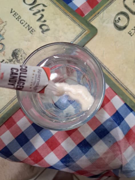 Collagen Candy powder poured into a glass of water.