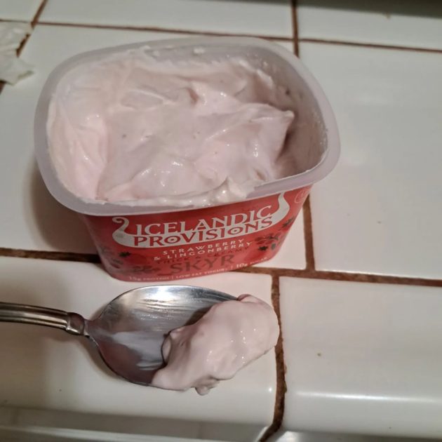 Icelandic provisions skyr yogurt on a spoon top view of container.