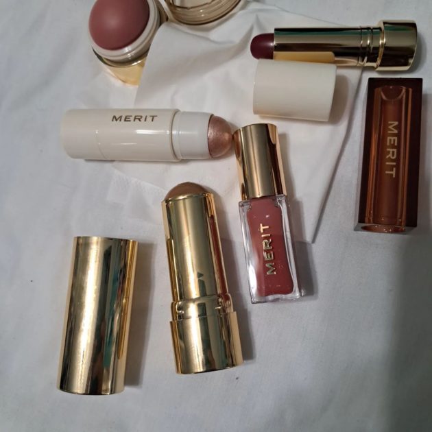 Merit beauty products. blush, lipstick, highlighter stick, bronzer stick, and lip oil.