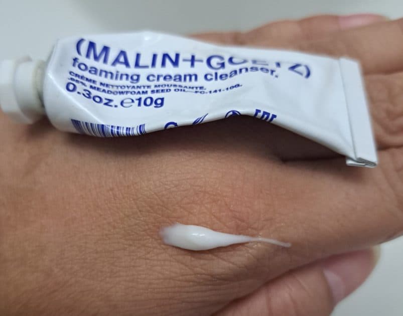 malin + goetz foaming cream cleanser tube and cleanser swatch. White cleanse on my hand along with a white tube with blue letters.