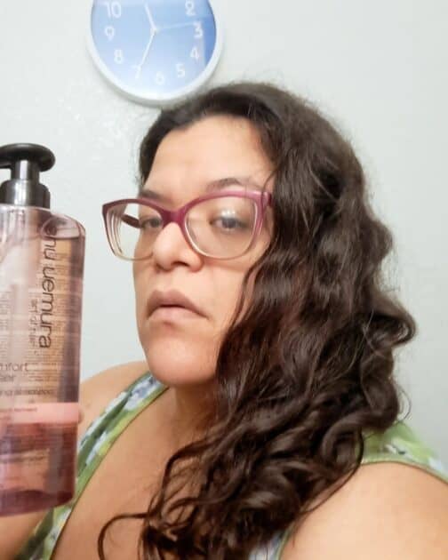 delicate comfort deep cleanser by shu Uemura clarifying shampoo bottle in my hand with a front view of my hair.