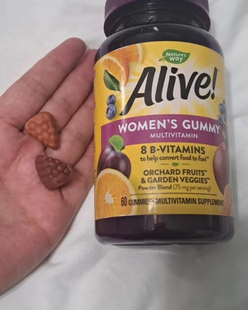 alive gummy vitamins for women in my hand with bottle next to my hand.