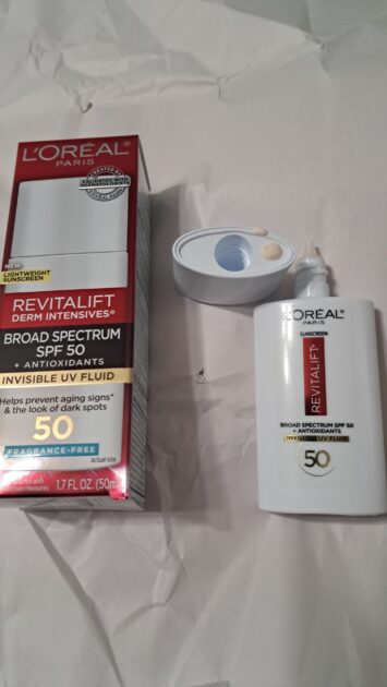 REVITALIFT DERM INTENSIVES Broad Spectrum SPF 50 Invisible UV Fluid box with spf bottle. lid removed with SPF on bottle lid.