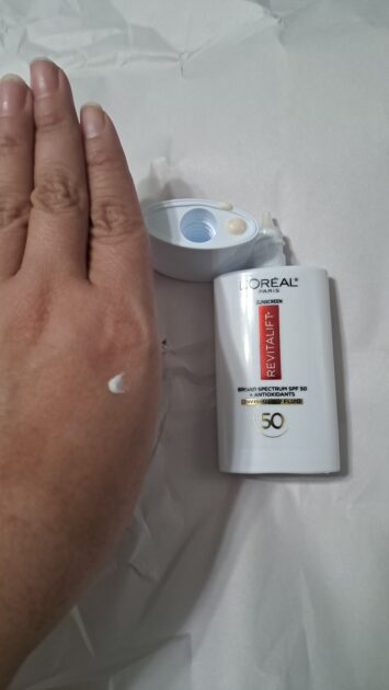 Broad Spectrum SPF 50 Invisible UV Fluid spf bottle. lid removed with SPF on bottle lid. A spot of SPF on my hand.