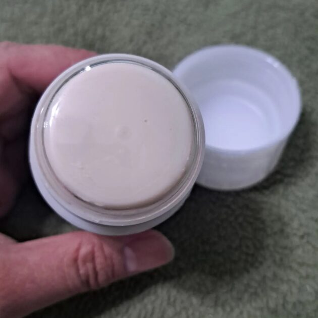 Donna Karan Cashmere mist deodorant stick lid removed with plastic protector covering deodorant stick. Beige-colored deodorant stick.