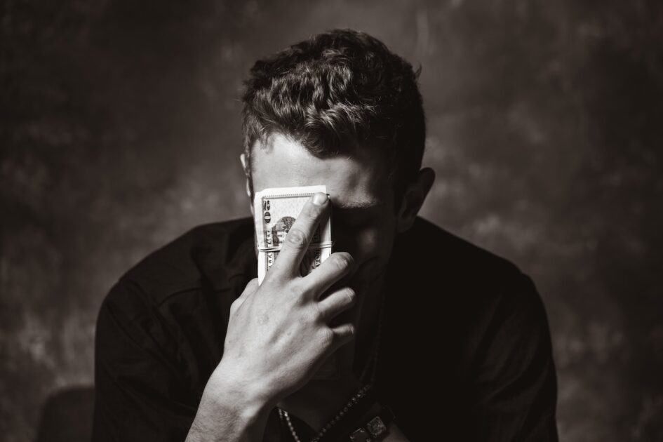 man holding banknote Photo by Travis Essinger image source Unsplash. image is in black and white.