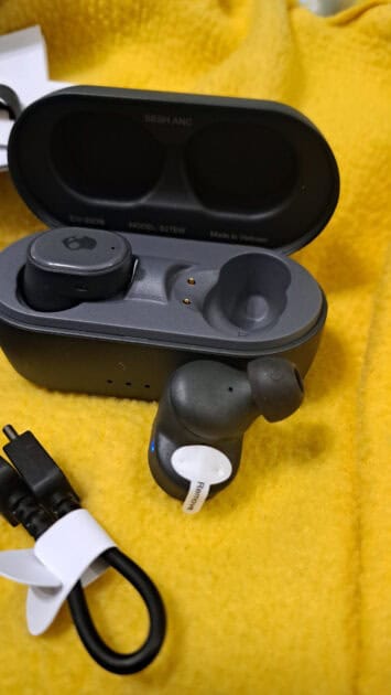 Skullcandy Sesh ANC earbud removed from case showing the earbud cover and protector on the charging nodes.