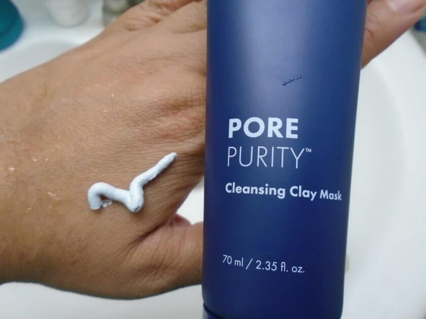 close up of the Hero Pore Purity cleansing clay mask tube with a ribbon of product on my hand. Dark navy tube with white text.