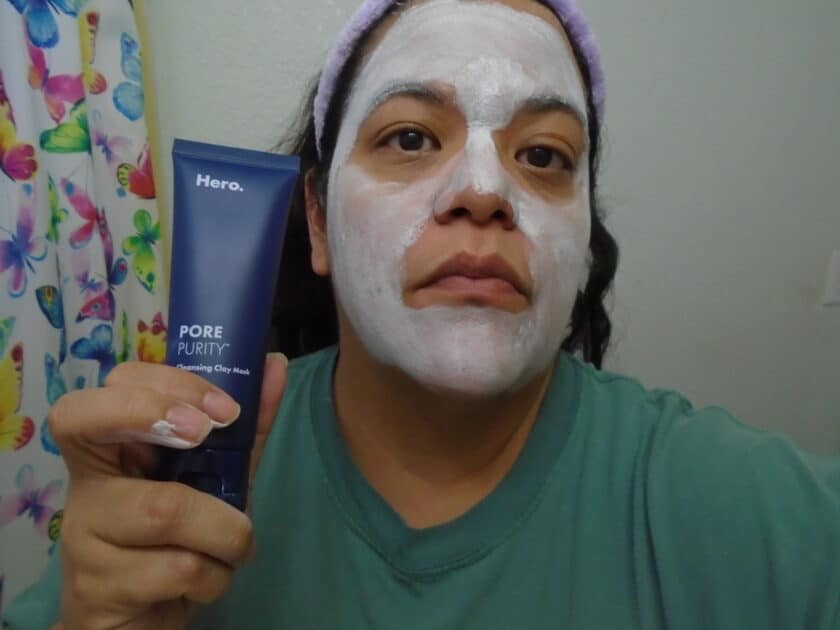 Hero Pore purity clay mask on my face while i hold up the product tube.