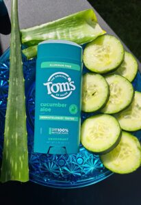 Toms of Main Cucumber aloe deoderant with cucumber slices and aloe leaves. On a blue plate.