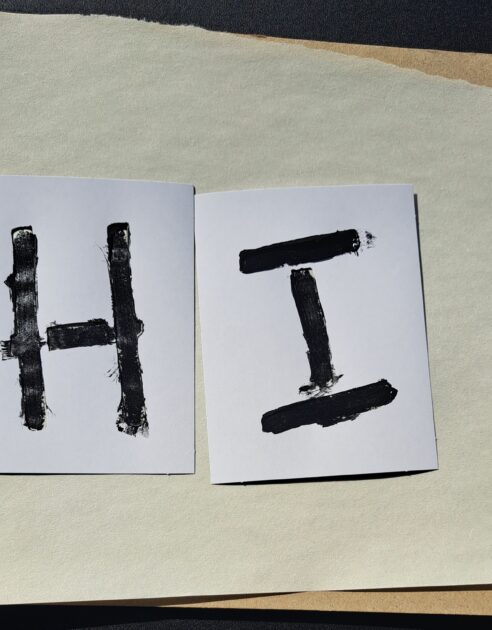 Stenciles in use on a sheet of construciton paper. letters used H and I.