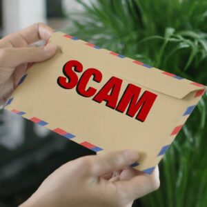 A letter with an envelope with bold red text reading Scam on it