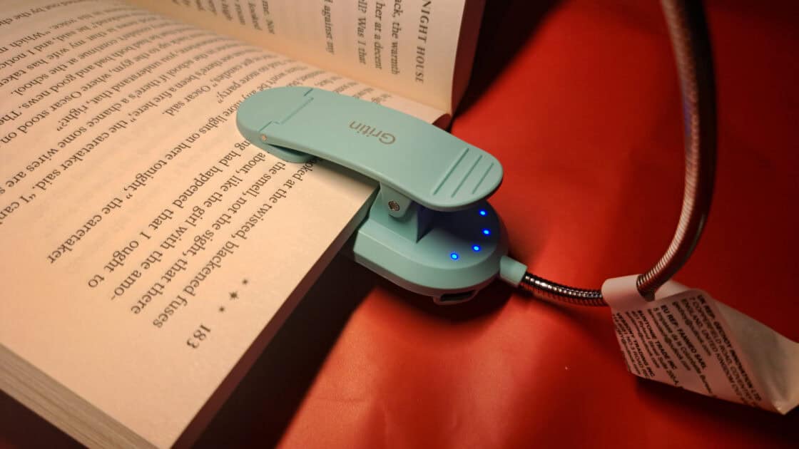 Gritin Rechargeable Book Light clipped to book with power indicators light and powered on.